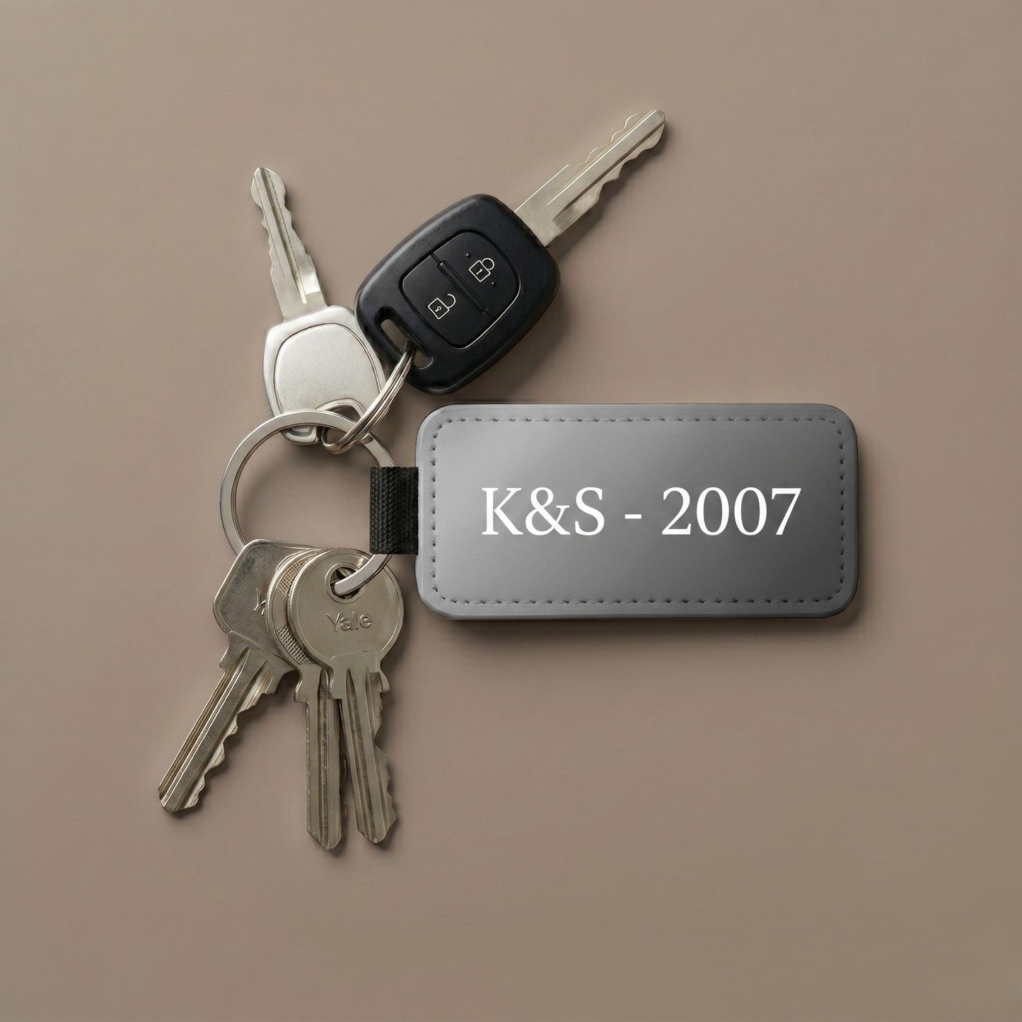 Personalizēts sublimācijas atslēgu piekariņš ar tekstu 'K&S - 2007' un pie automašīnas un mājas atslēgām