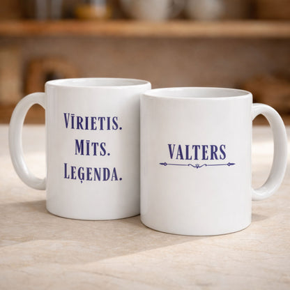 Divas baltas keramikas krūzes ar uzrakstu "Vīrietis. Mīts. Leģenda." un personalizētu vārdu uz virtuves fona