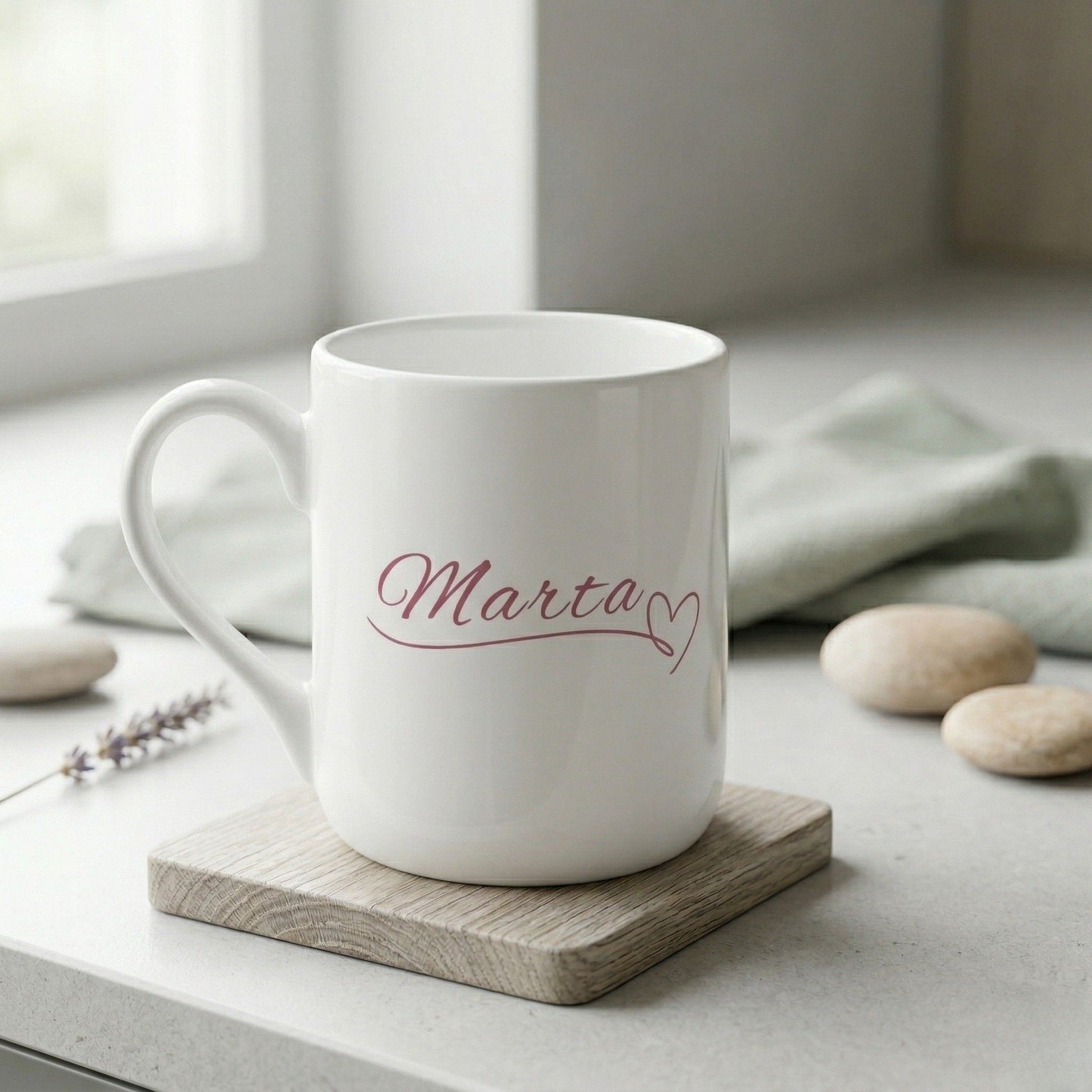 Personalizēta balta keramikas dāvanu krūze ar elegantā kaligrāfijas fontā uzrakstītu vārdu "Marta" un sirsniņu.