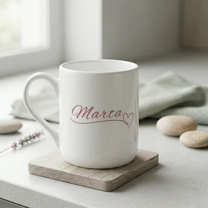 Personalizēta balta keramikas dāvanu krūze ar elegantā kaligrāfijas fontā uzrakstītu vārdu "Marta" un sirsniņu.