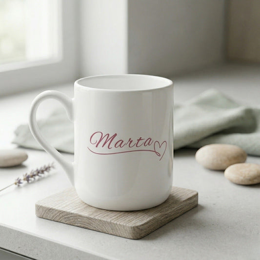 Personalizēta balta keramikas dāvanu krūze ar elegantā kaligrāfijas fontā uzrakstītu vārdu "Marta" un sirsniņu.