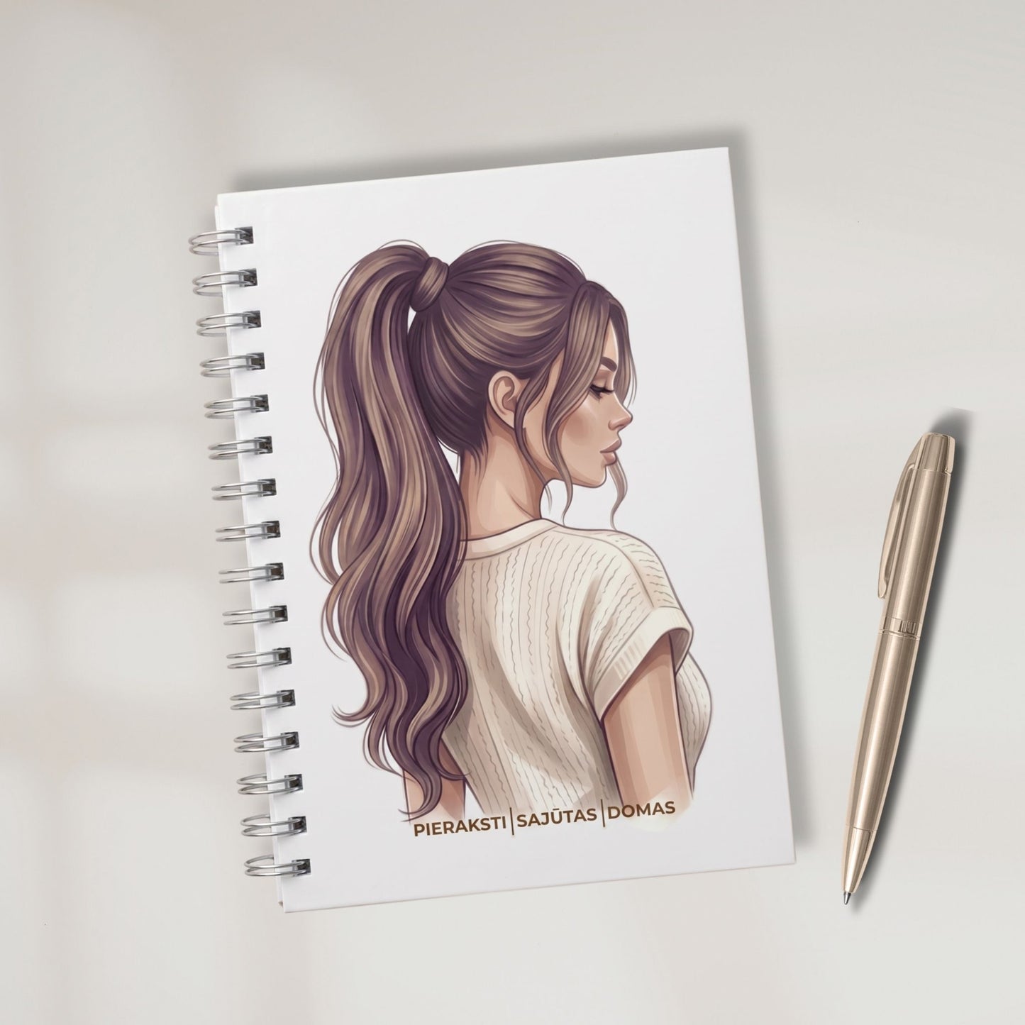 Minimālistiska balta pierakstu klade ar sievietes ilustrāciju un zelta krāsas pildspalvu. Teksts uz vāka: Pieraksti, Sajūtas, Domas.