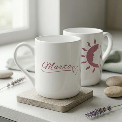 Divpusējas dizaina keramikas krūzes komplekts ar personalizētu vārdu "Marta" un grafisku saules siluetu uz rīta kafijas galda.