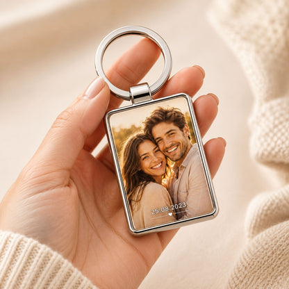 Personalizēts metāla atslēgu piekariņš ar foto turēts rokā pie atslēgām.